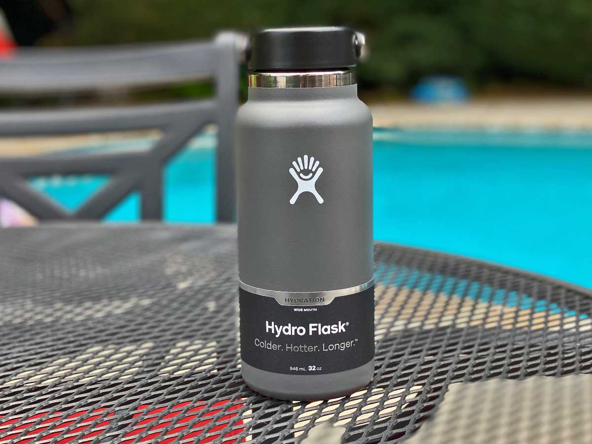 brand name water bottle sitting on an outdoor table by a pool