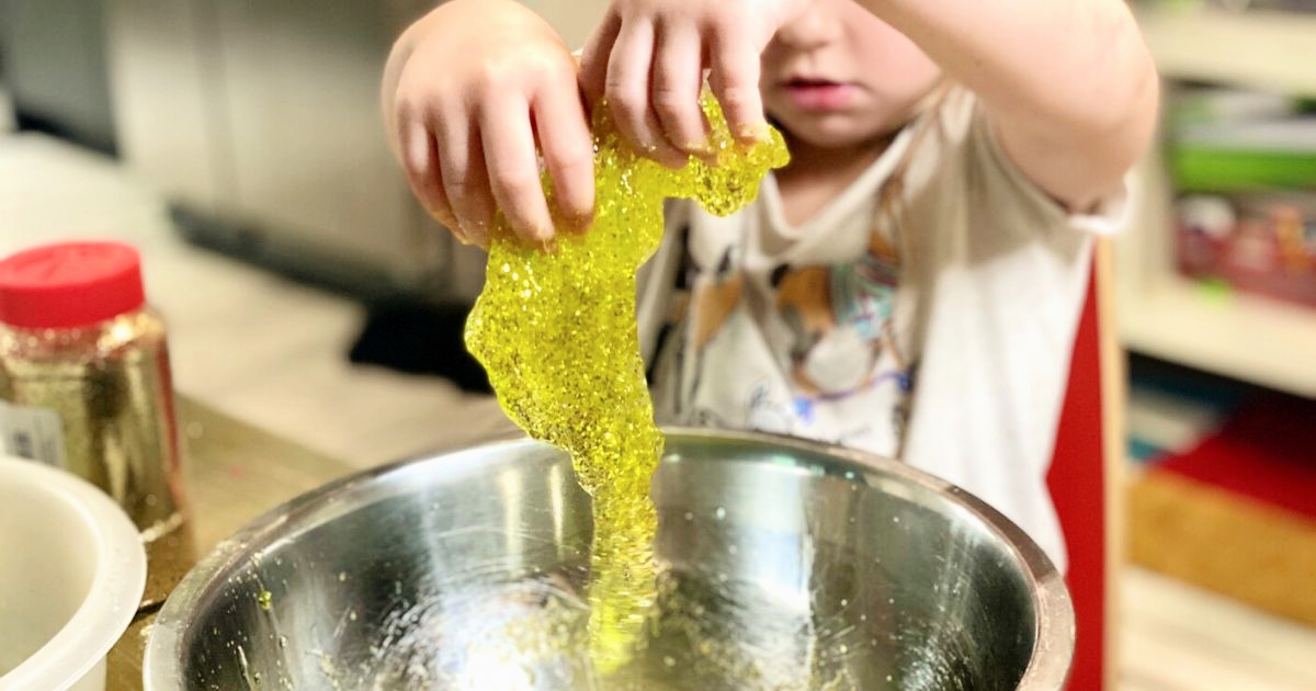 Girl pulling diy slime out of a metal bowl