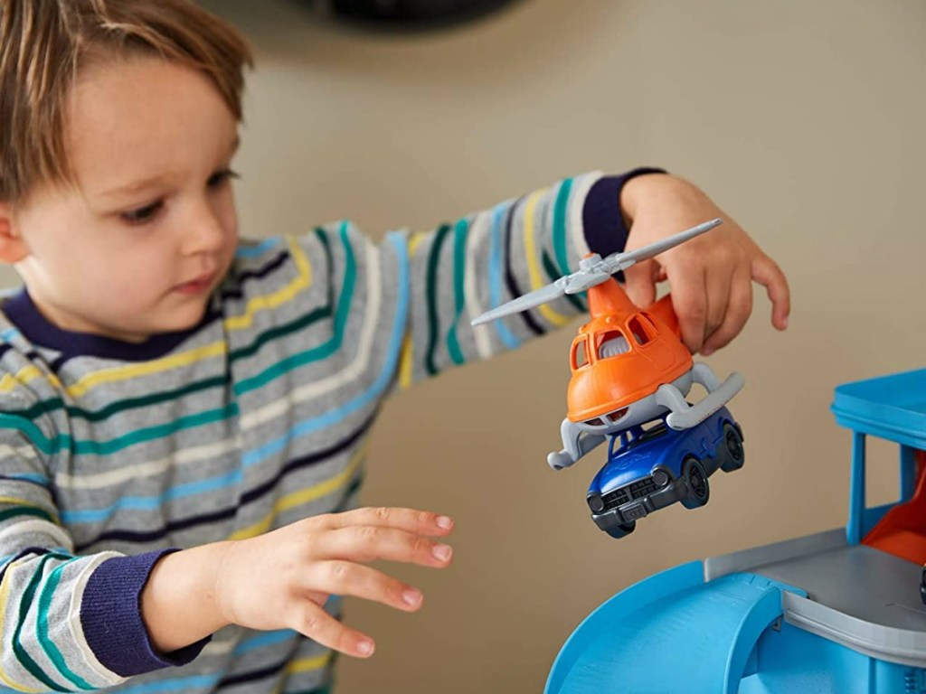 little boy playing with helicopter and car toys