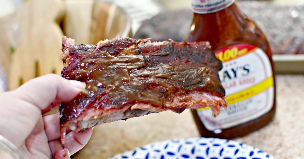holding bbq ribs with BBQ sauce on counter