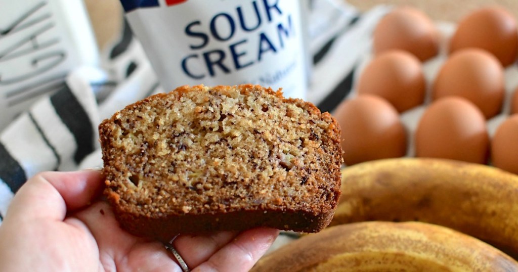 holding banana bread with sour cream in background 