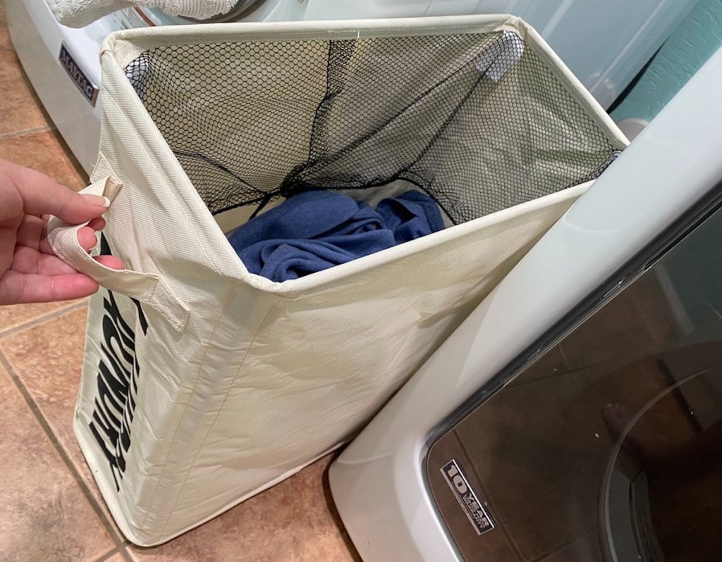 hand pulling out laundry basket between washer and dryer