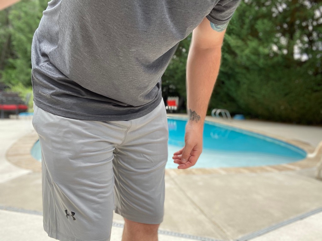 man in ua gray shorts with pool in background 