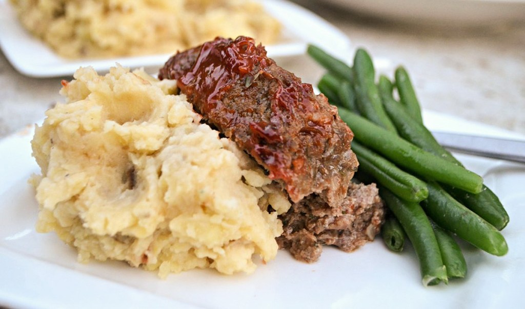 meatloaf on a plate with potatoes and green beans