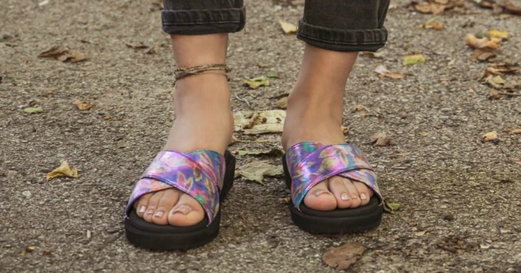 feet wearing purple sandals near leaves
