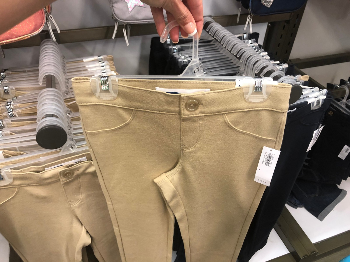 person holding up pair of girls uniform pants on a hanger