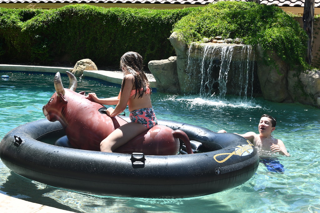 kids in pool with girl riding giant bull pool float 