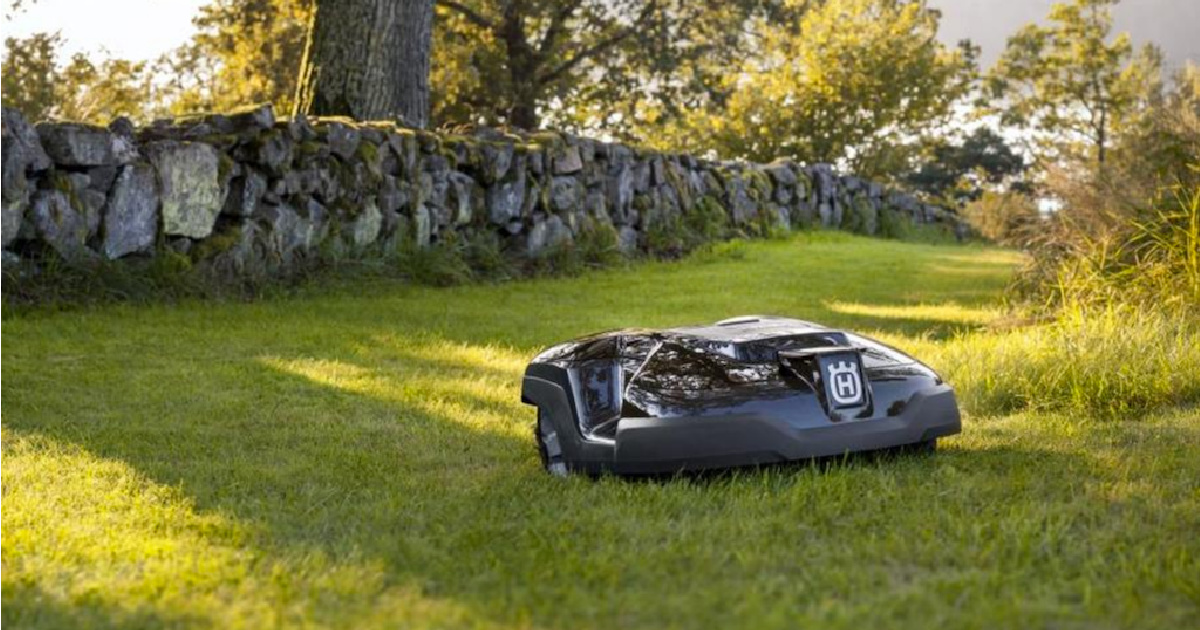 robot lawn mower device in yard in front of rock wall