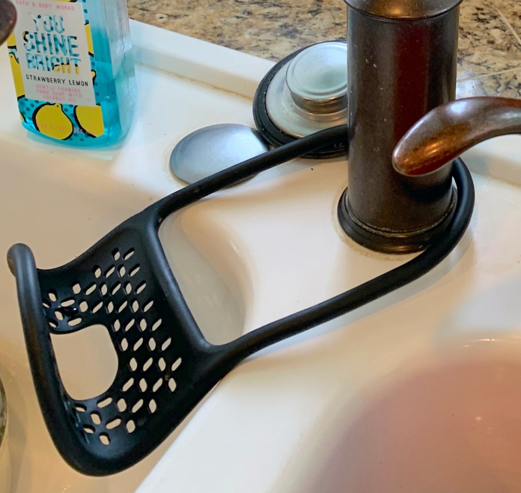 black sponge holder on sink faucet in white sink
