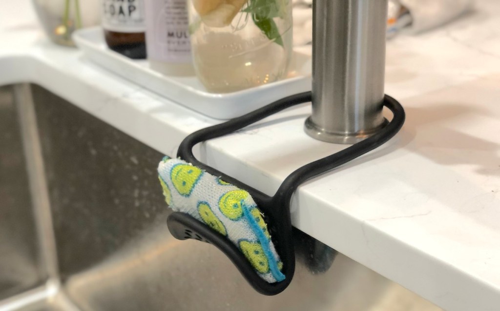 sponge inside black sponge holder wrapped around faucet in kitchen