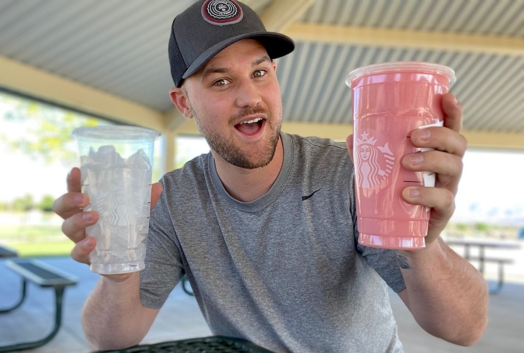 man holding two starbucks cup one with ice and another with pink drink 