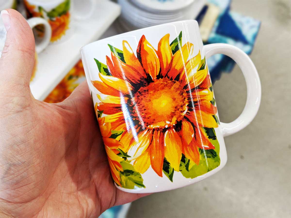 hand holding a sunflower mug up in a store