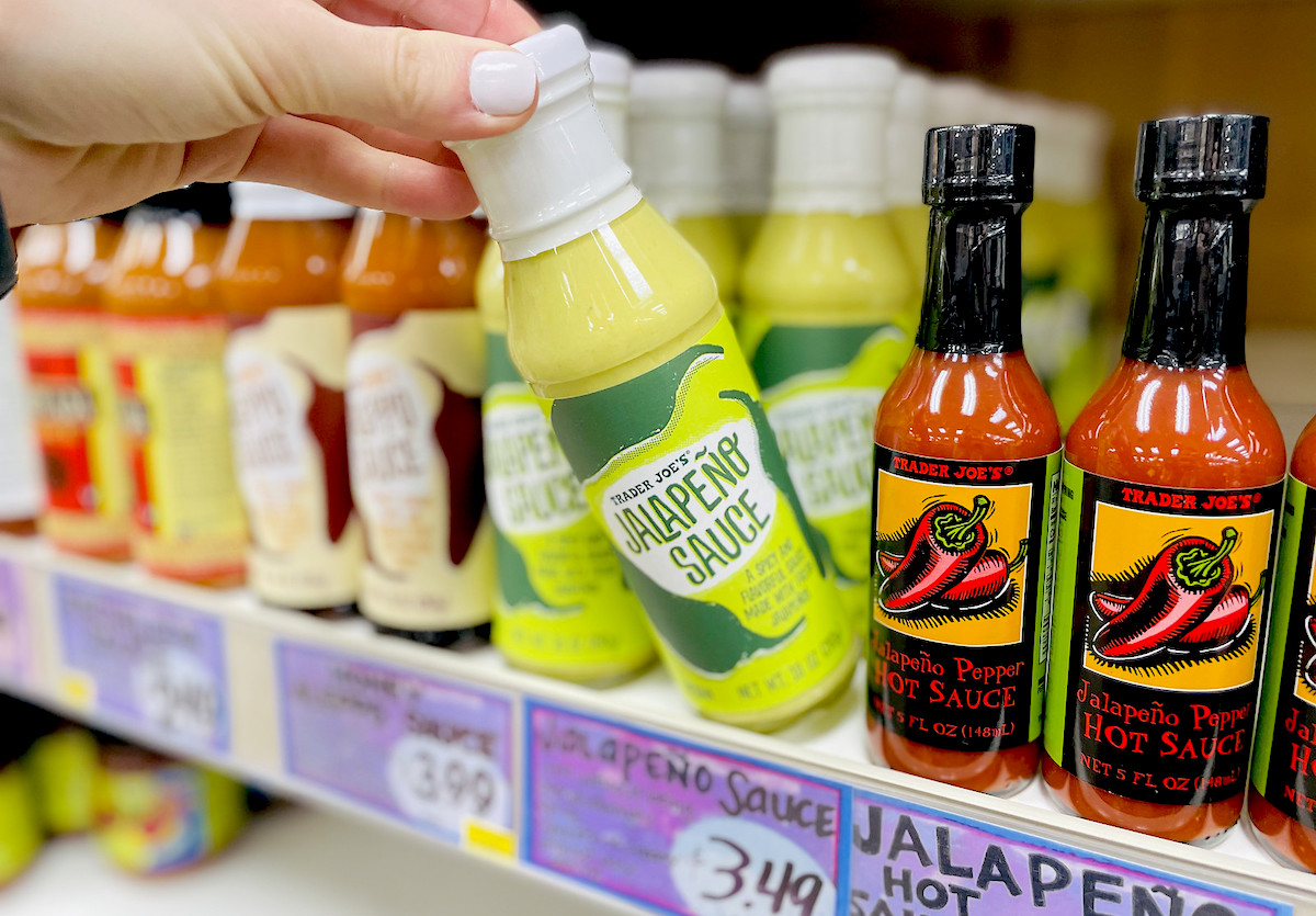 hand pulling green bottle of jalapeno sauce off shelf - best Trader Joe's items