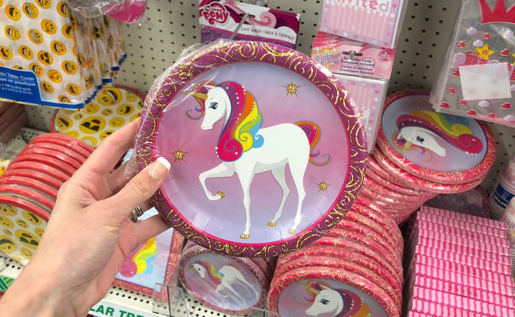 hand holding a pink and rainbow pack of unicorn plates in store aisle