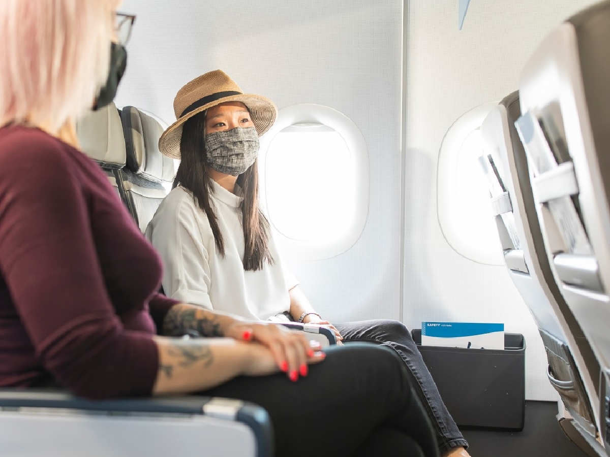 two women wearing face masks on airplane