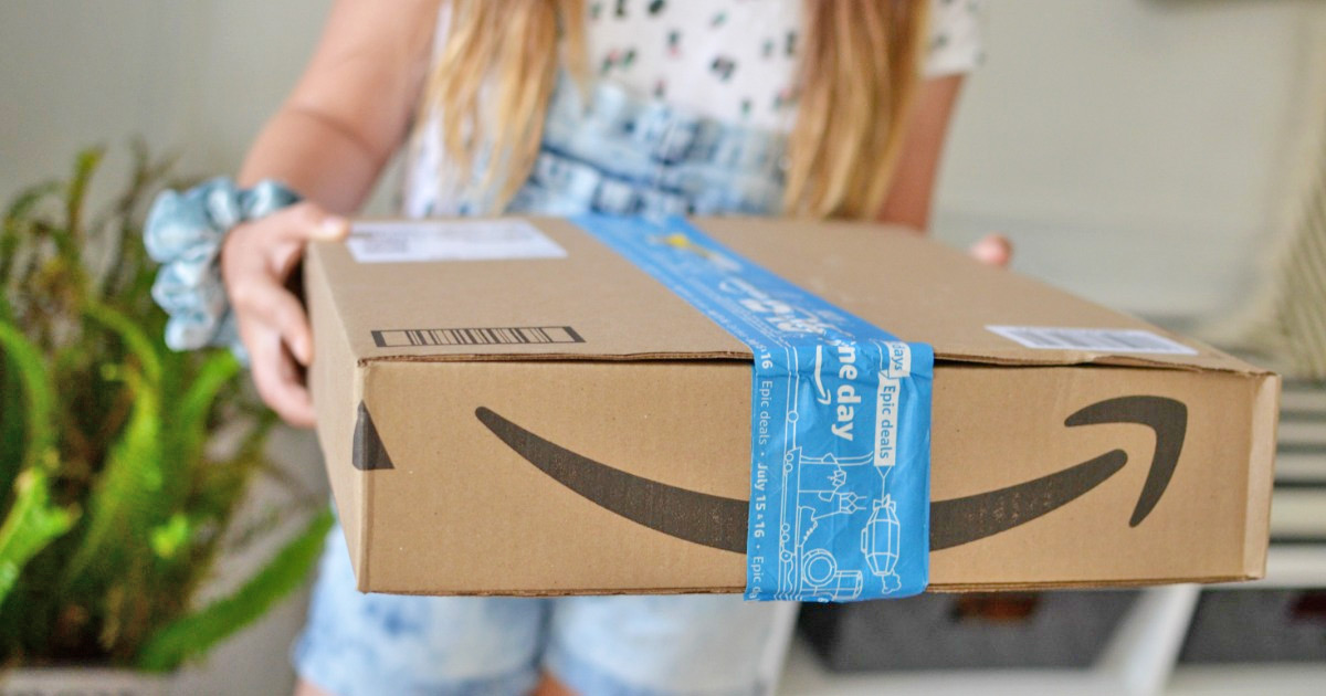 Frau, die eine Amazon-Schachtel mit blau bedrucktem Paketklebeband hochhält