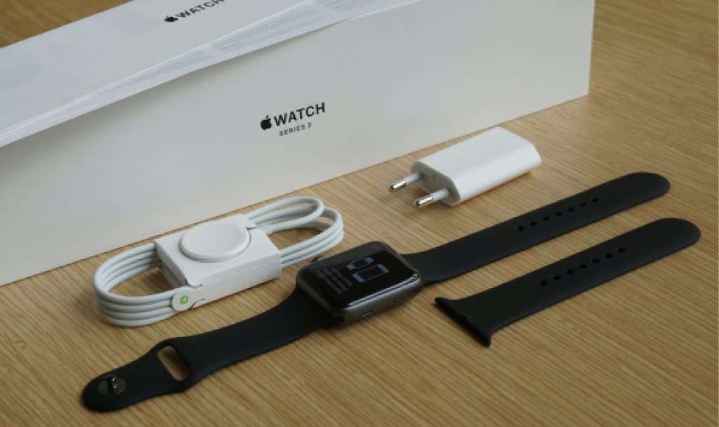 black Apple watch, accessories, and box on table