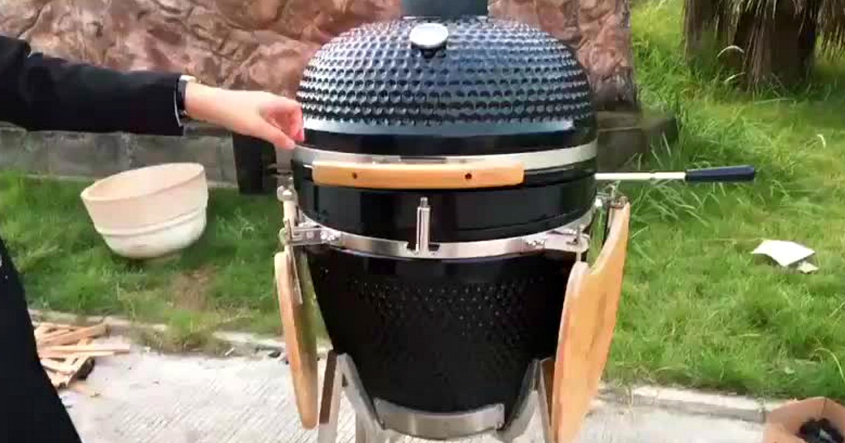 hand touching the side of an egg shaped grill