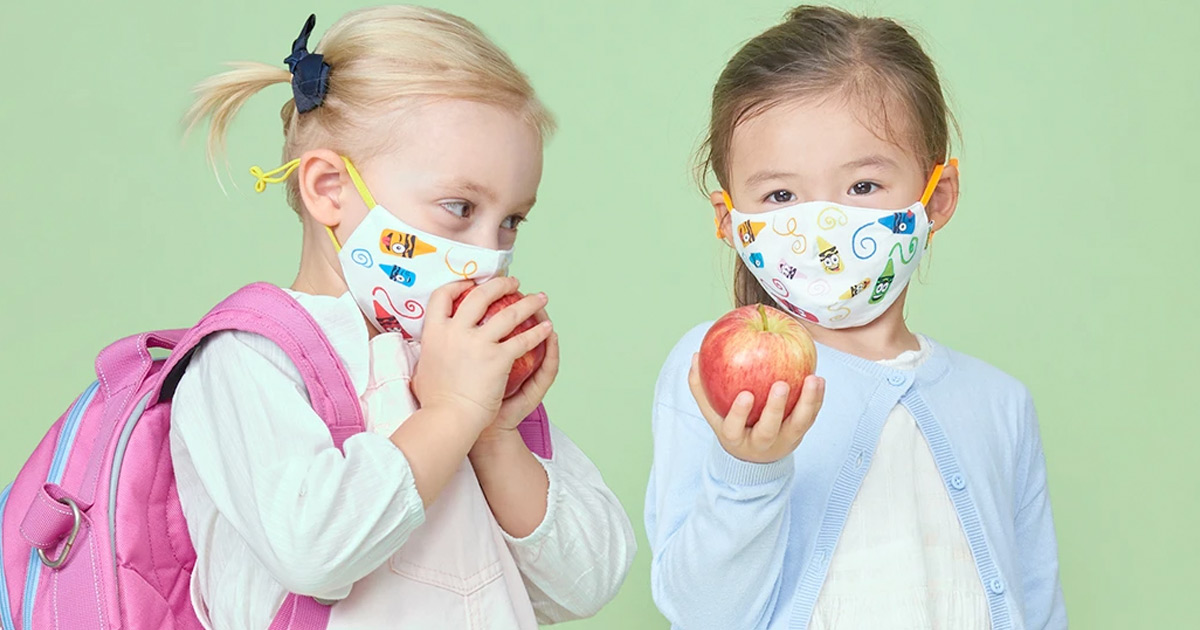 two girls holding apples and wearing crayola theme face masks