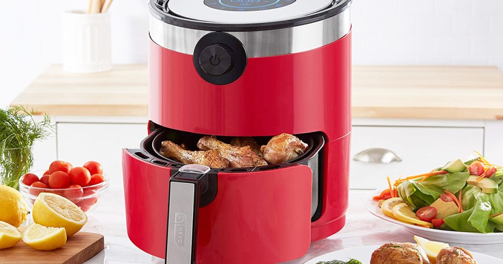round red air fryer on kitchen counter with basket open showing fried chicken inside
