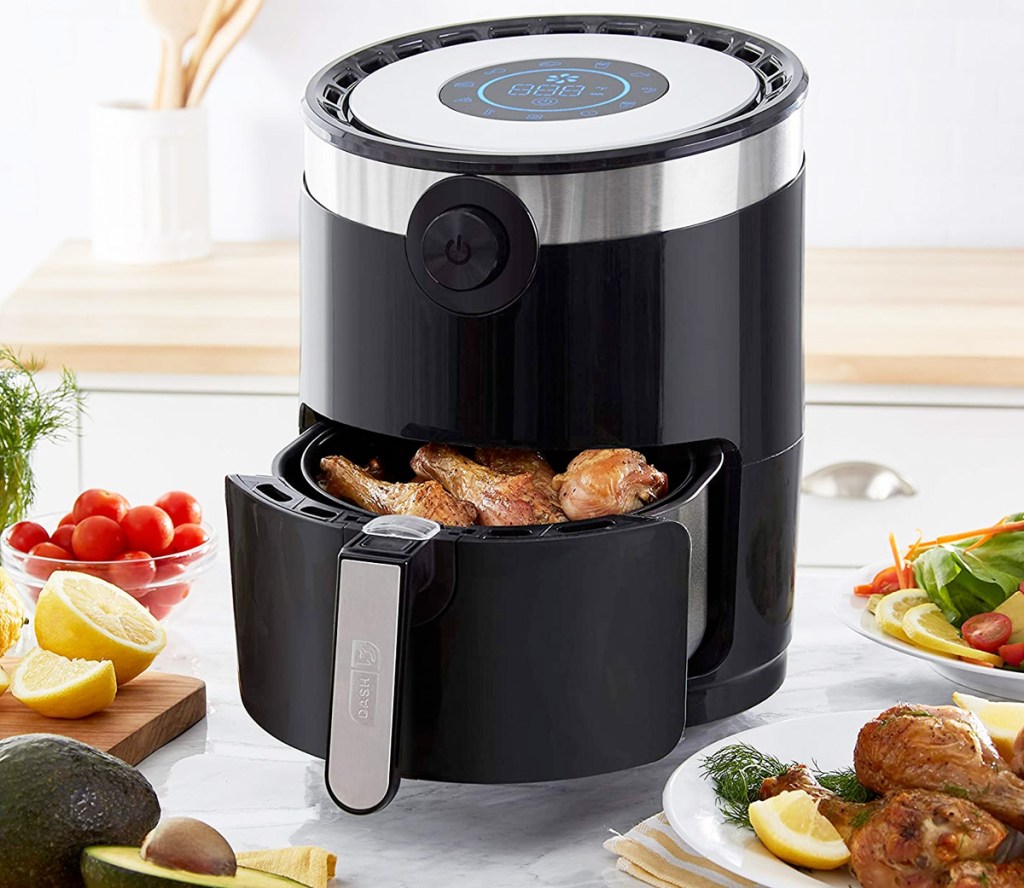 round black air fryer on counter with basket open showing fried chicken inside