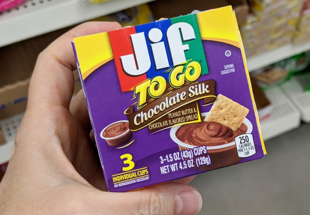 person holding up a purple box of jif to-go chocolate silk cups