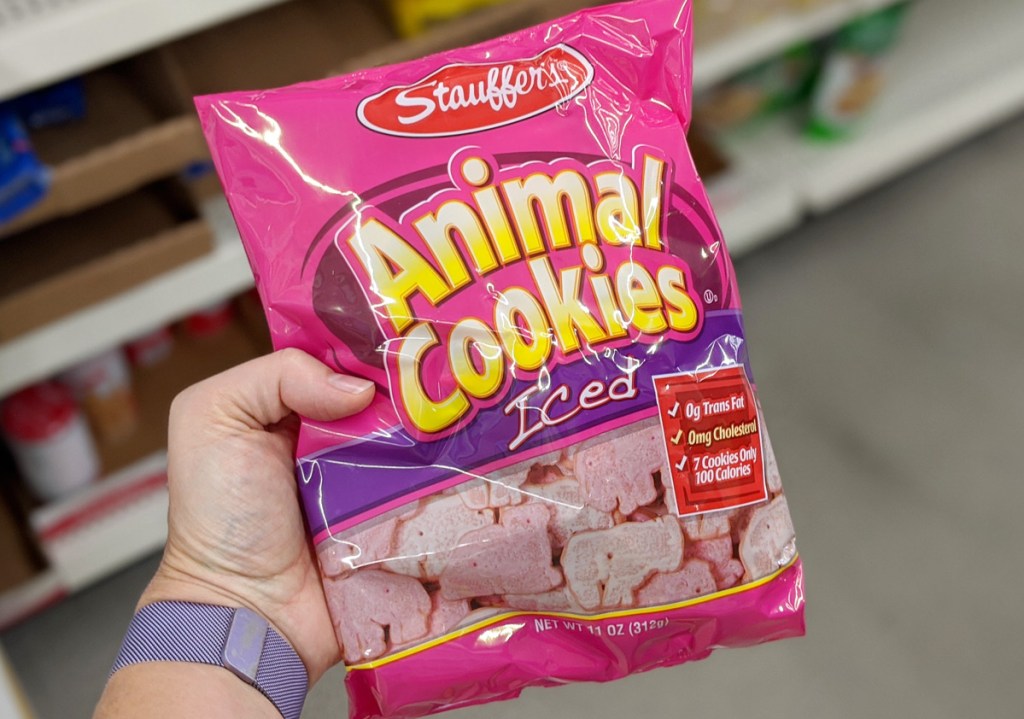 person holding up a pink bag of iced animal cookies