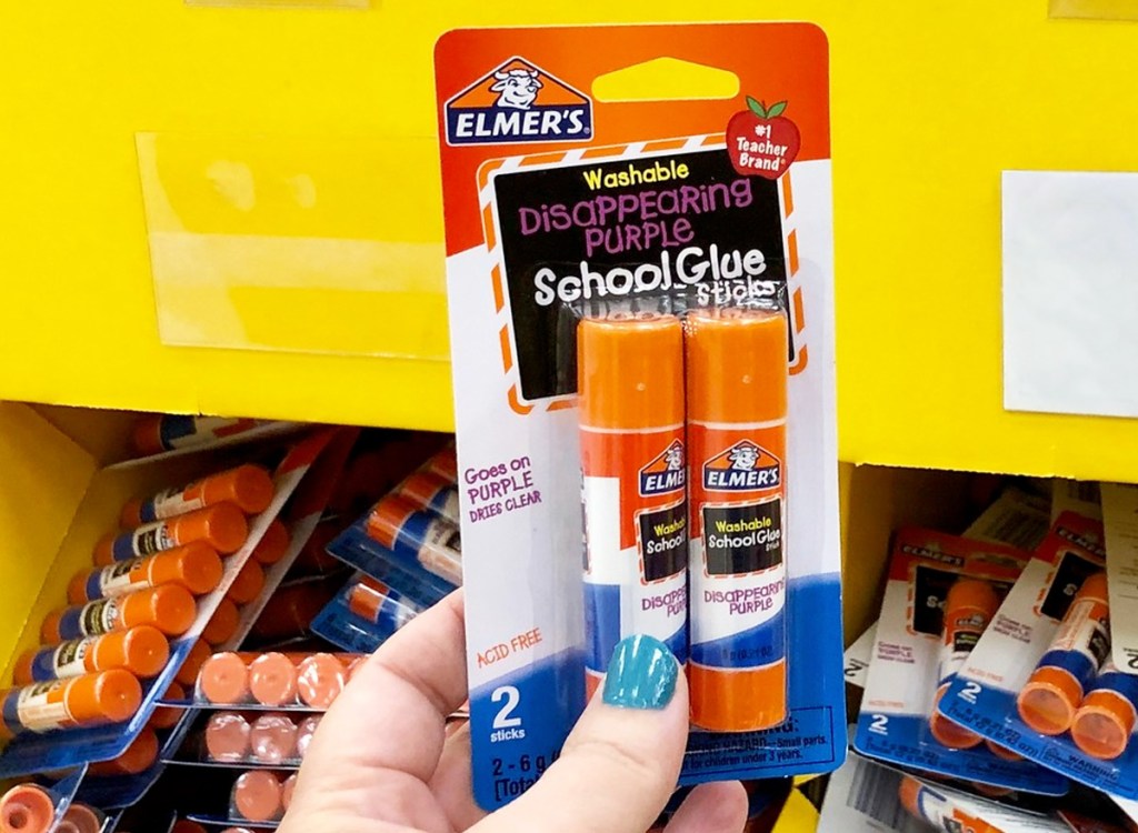 person holding up 2-pack package of elmers disappearing purple glue sticks