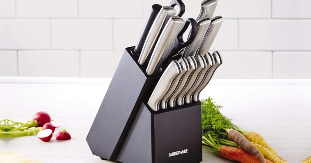 black knife block with stainless steel cutlery on counter with various vegetables