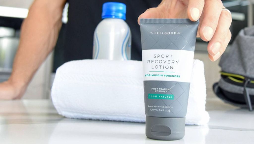 Feelgood Lab Sport Recovery Lotion on table with person standing behind the table