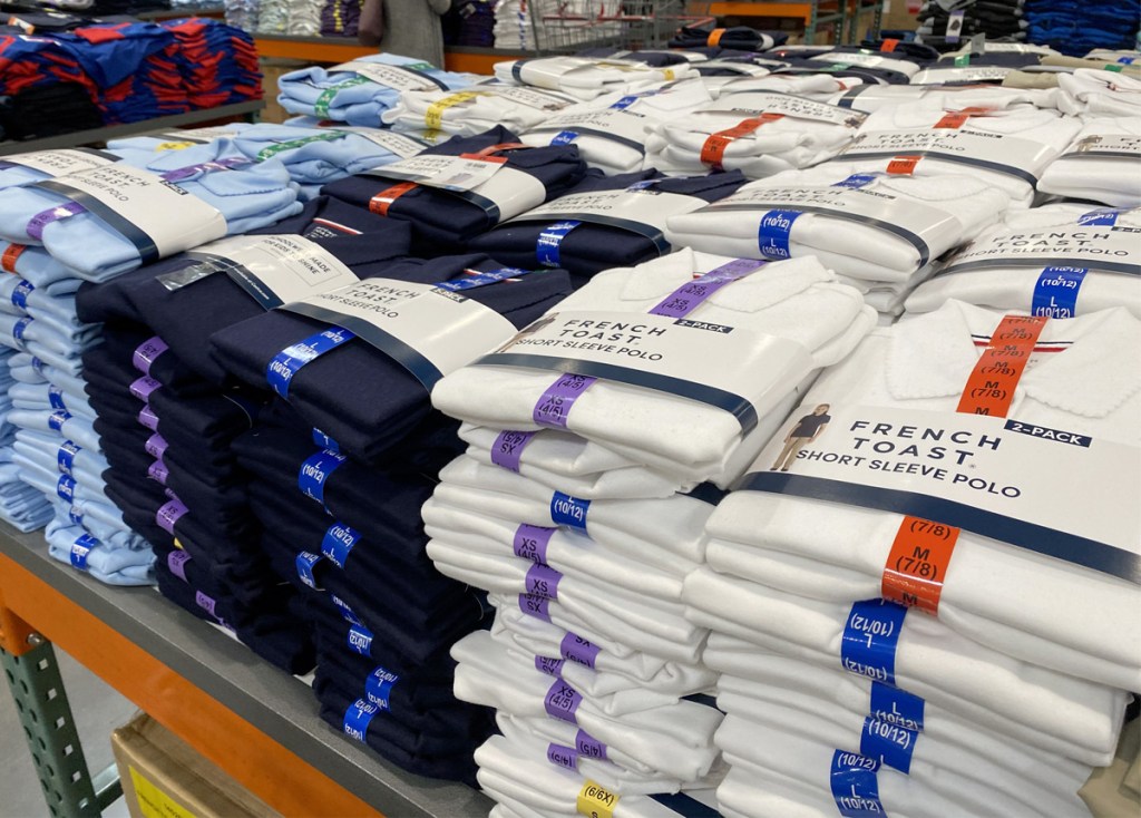 store display table full of 2-packs of girls school uniform polos in light blue, navy, and white
