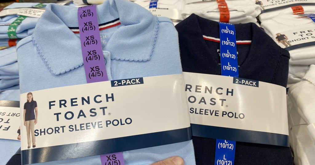 person holding up 2-packs of kids school uniform polos in light blue and navy colors