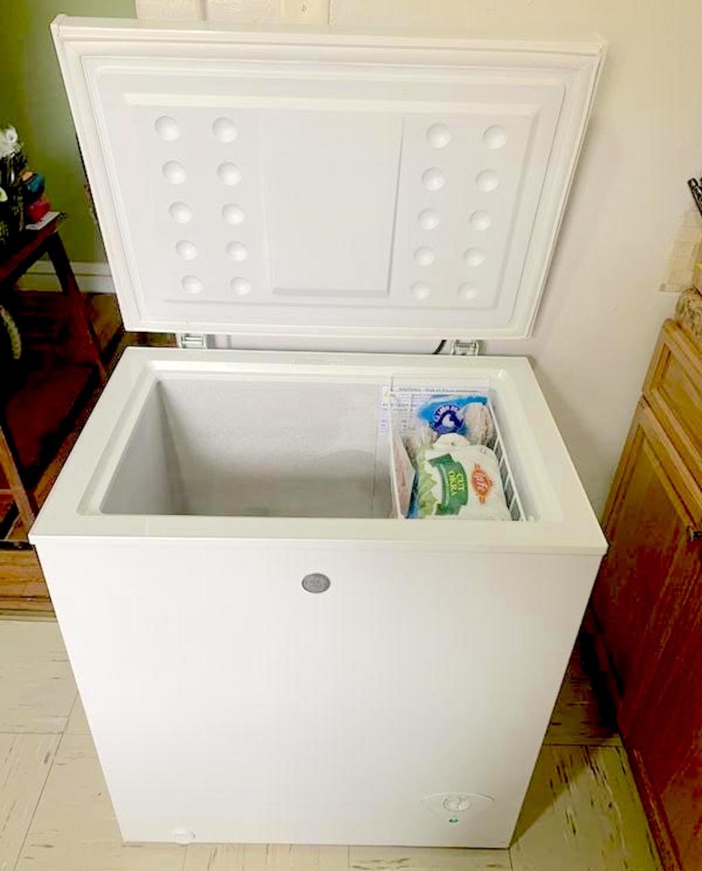 small white deep freezer sitting on floor with lid open