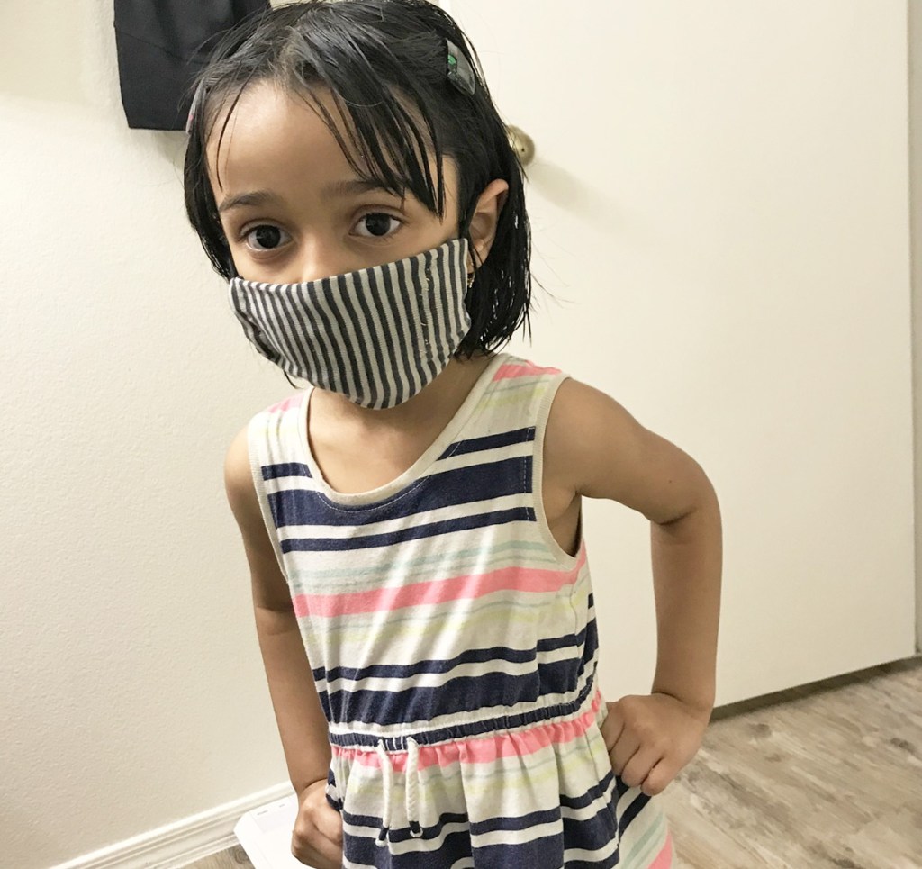 girl in striped dress wearing a black and white striped face mask