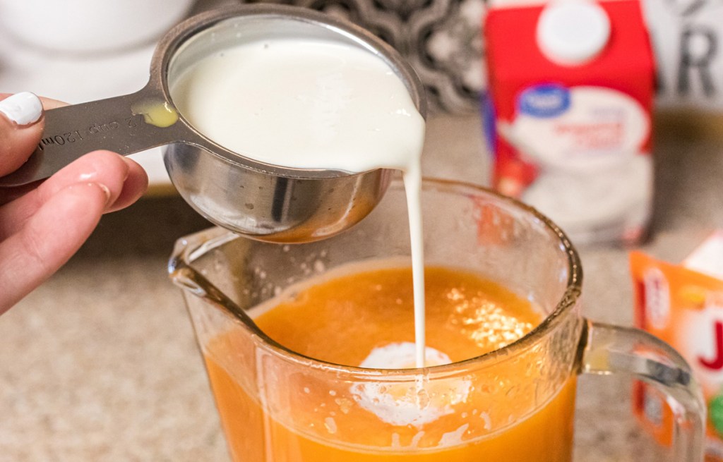 heavy cream being added to orange popsicle mixture