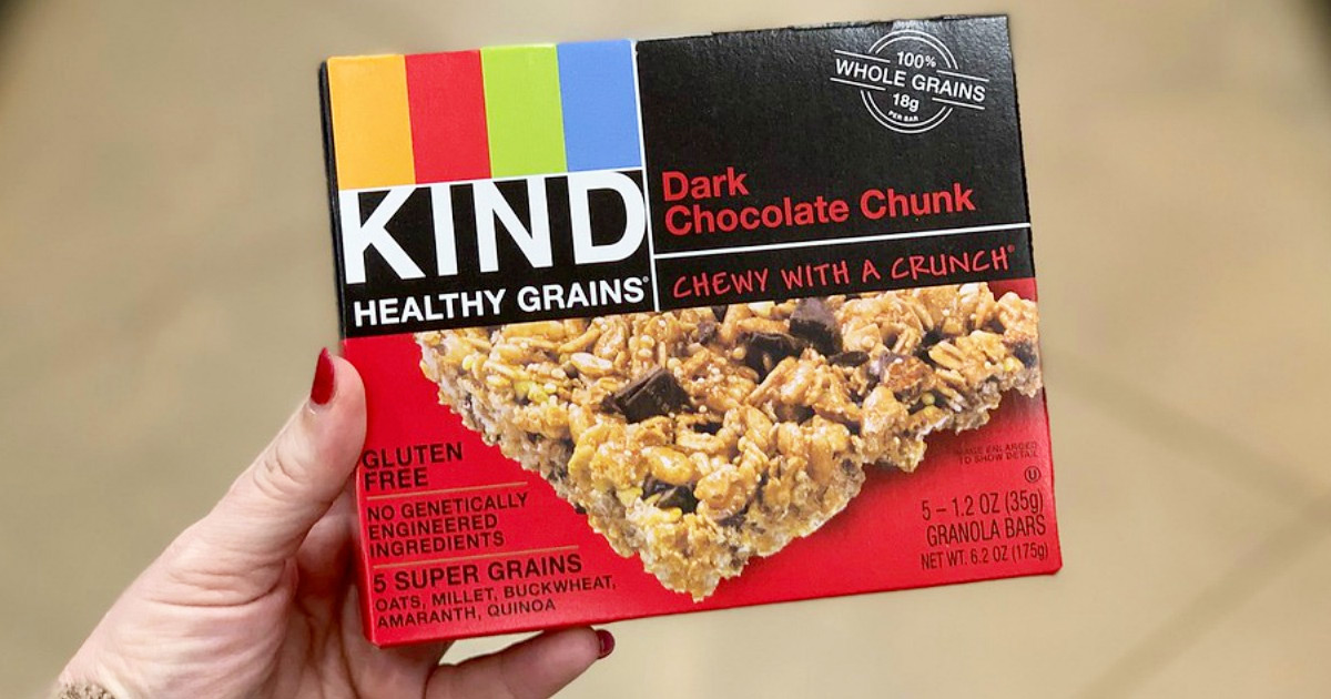 person with red nails holding up a red box of kind bars in dark chocolate chunk flavor