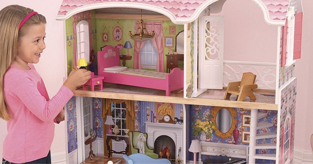 little girl playing with a huge dollhouse