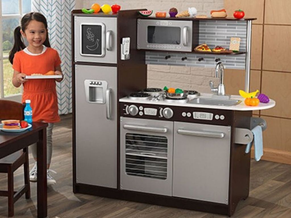 large play kitchen with a little girl playing with it 