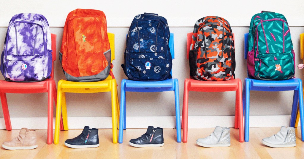 kids backpacks on lined up chairs with pairs of shoes under them