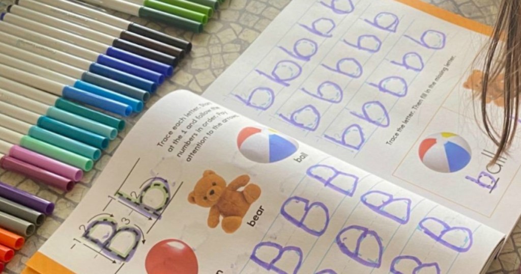 kids workbook with markers next to it