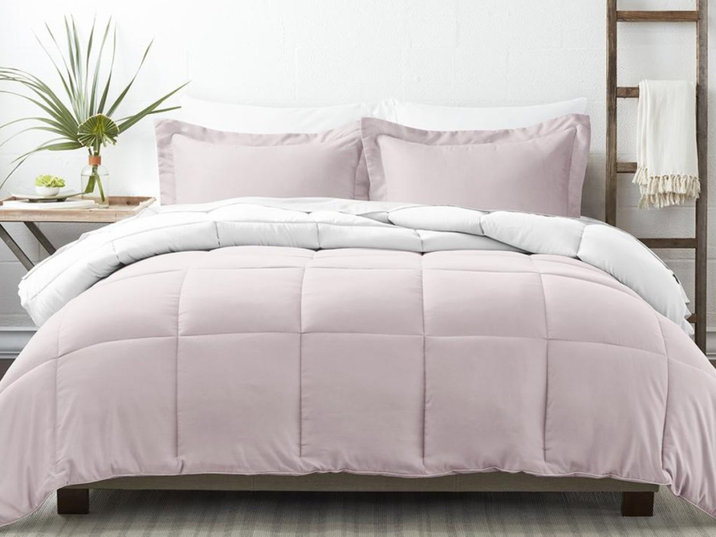 Light pink alternative down reversible comforter set on a bed with shams and pillows
