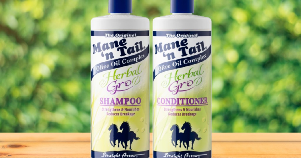 two bottles of shampoo on table with greenery in background