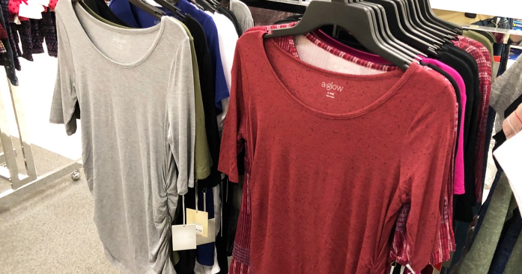 grey and red maternity tops hanging on hangers on store display racks
