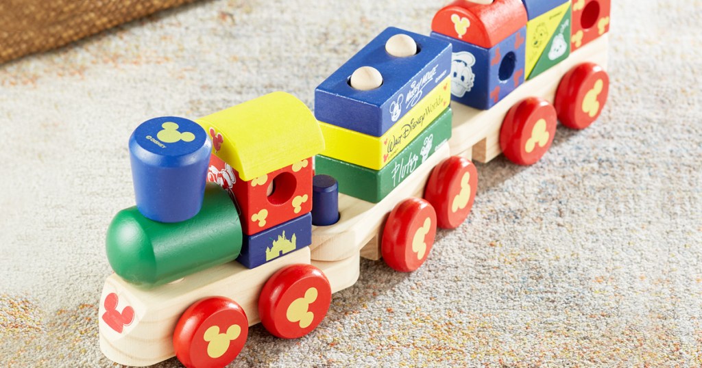 colorful wooden disney themed train with stackable cargo pieces on carpet