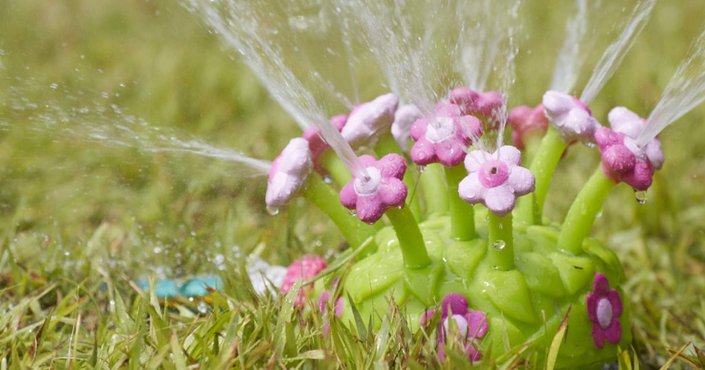 pink flowered petal sprinkler in grass shooting up water