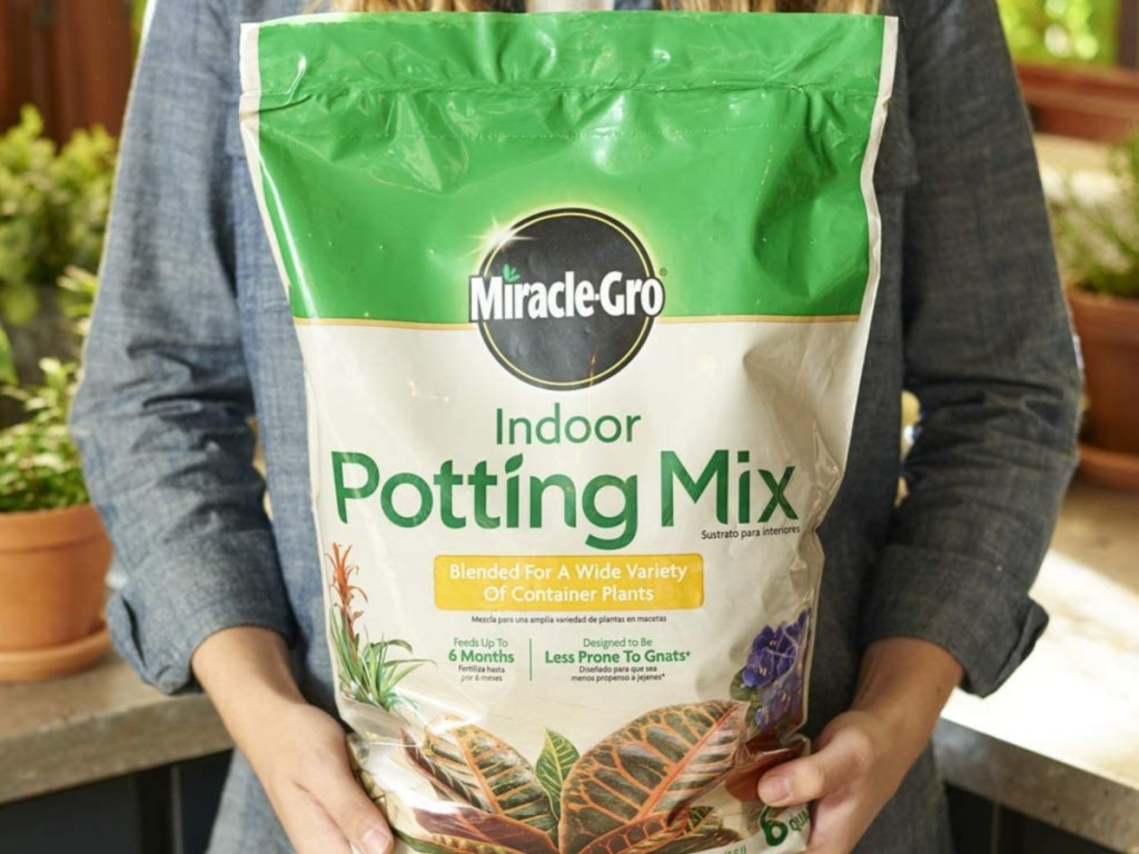 woman holding a 6 quart bag of miracle gro potting soil