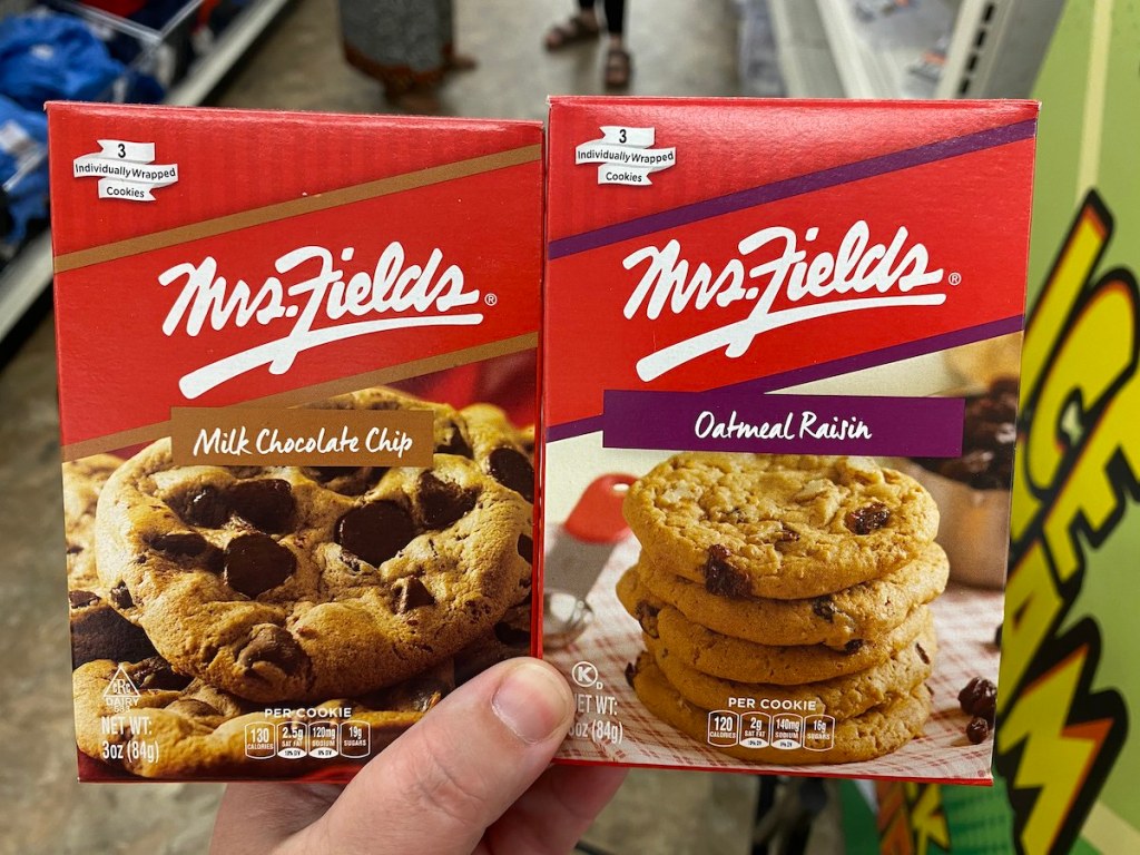 hand holding up boxes of Mrs. Fields Individually Wrapped Cookies chocolate chip and oatmeal raisin