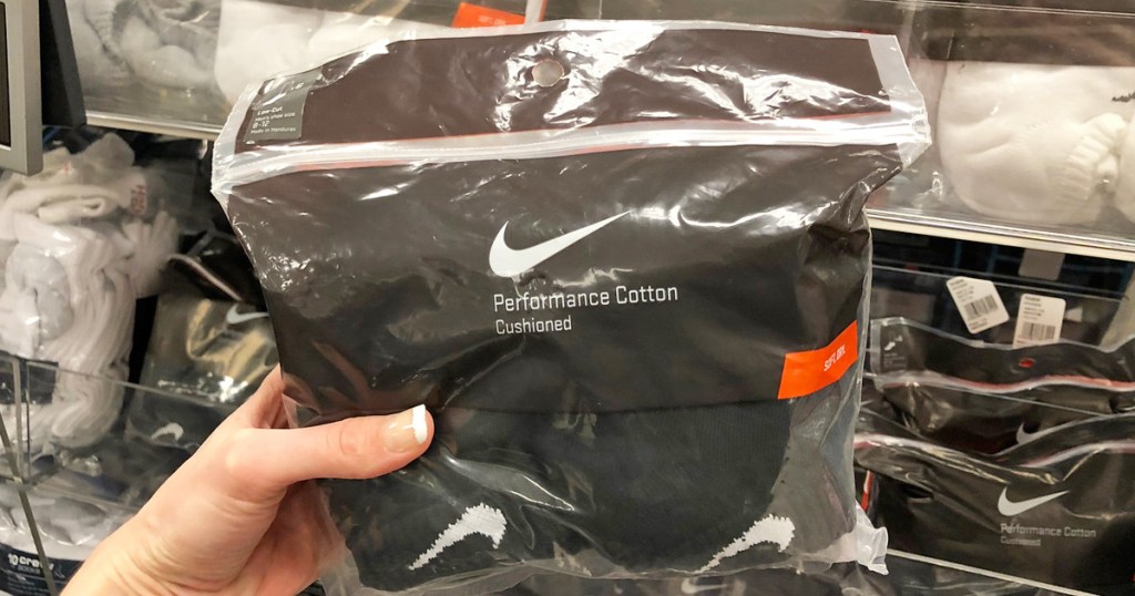 person holding up a plastic package of mens black nike socks