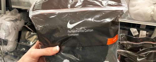 person holding up a plastic package of mens black nike socks