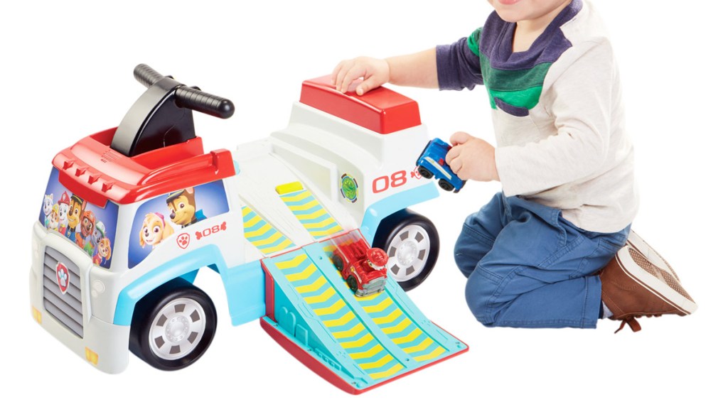 boy playing with cars on a ramp coming from a paw patrol themed ride-on toy